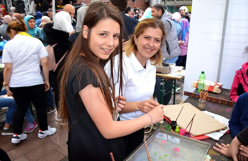Ayla Eskin vom Zukunft Bildungswerk zeigt Dyaa (10) die Kunst des Wassermalens, auch Ebru genannt.