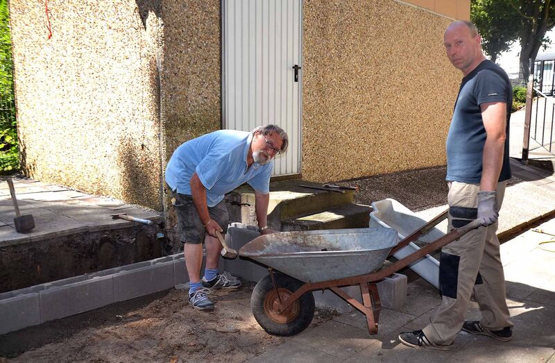 Der AWO-Ortsvereinsvorsitzende Theo Hackmann und sein Stellvertreter Olaf Dittmer (v.l.) plattieren vor dem Sommerfest den alten Müll-Sammelplatz an der Begegnungsstätte Sartoriusstraße neu. Foto: AWO Essen